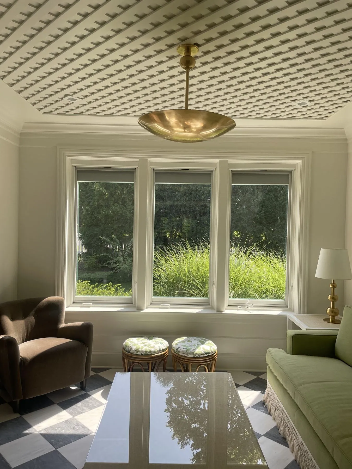 Furnished sunroom with a checkerboard floor and brass pendant