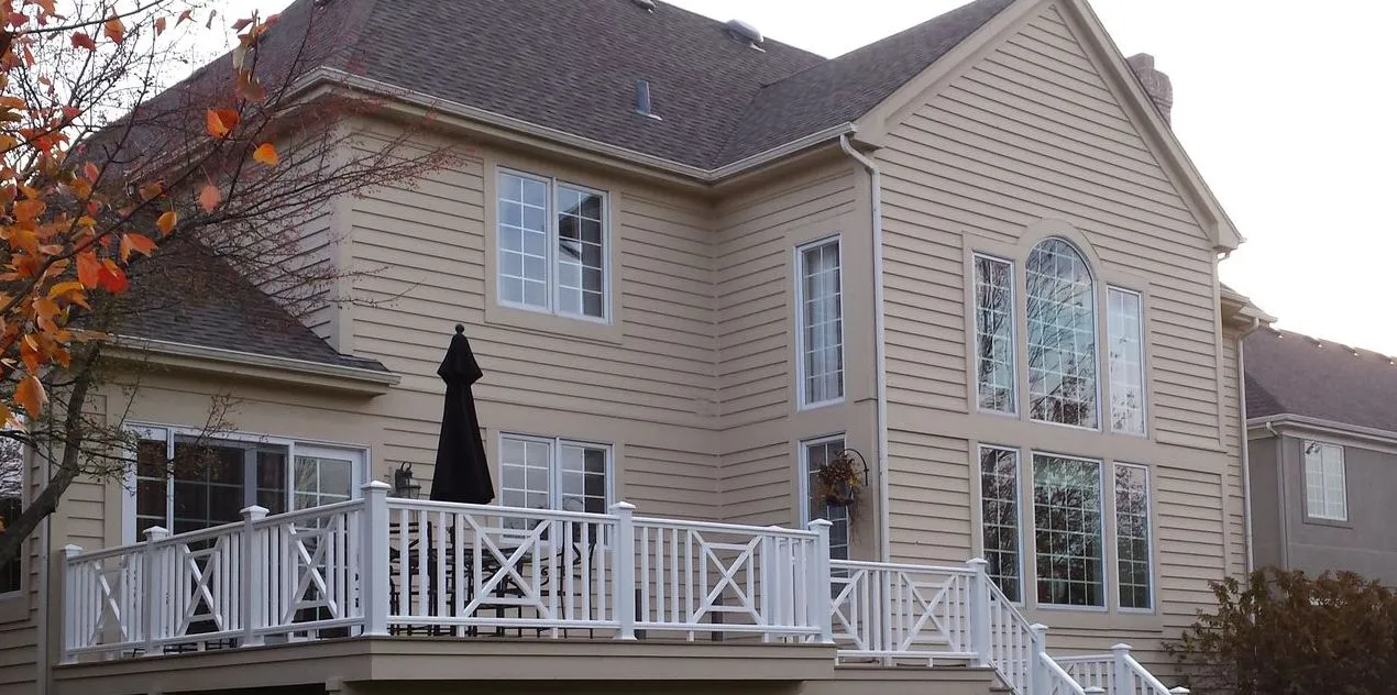 Deck with white X-pattern railings across the back of a home