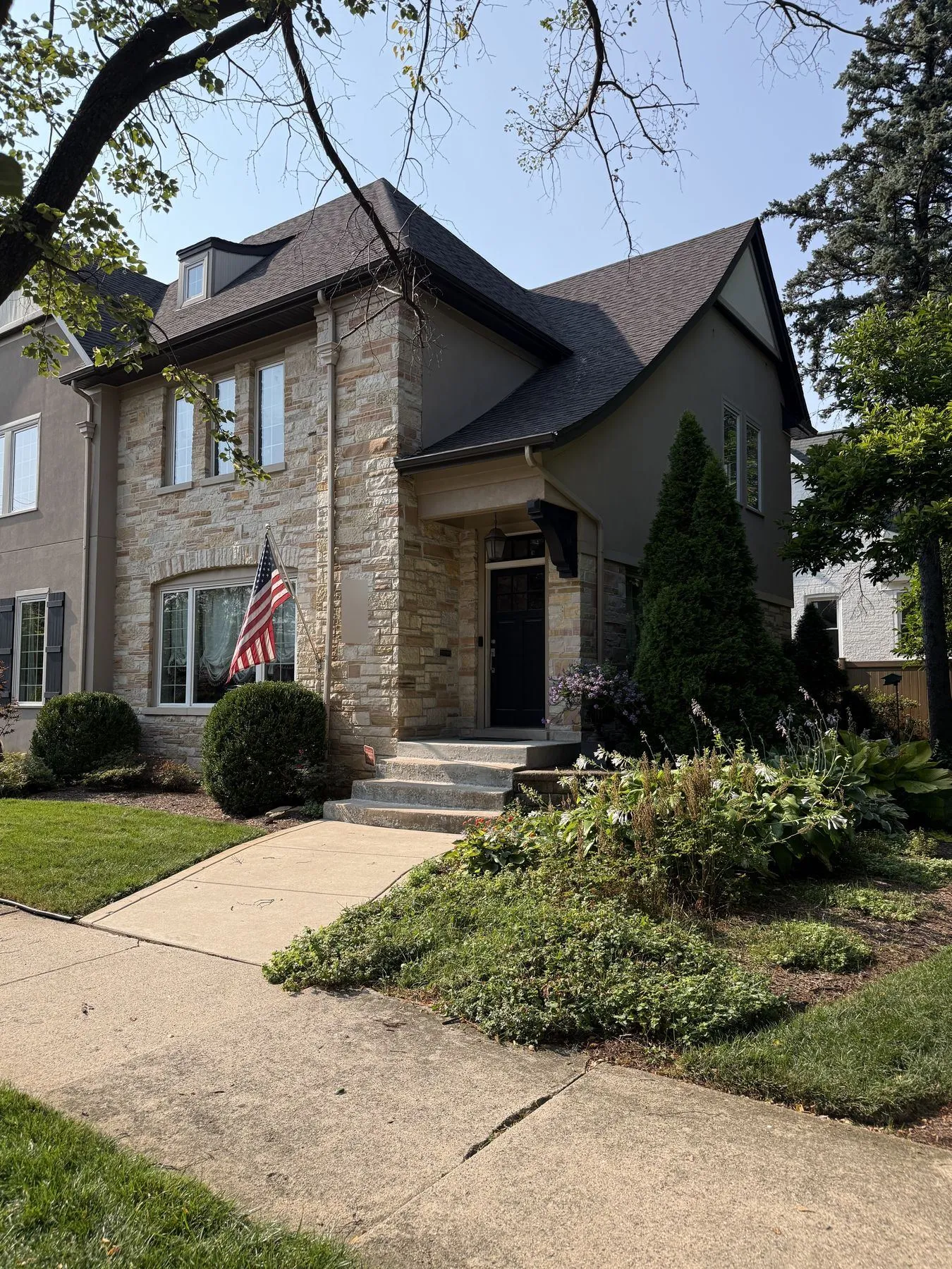 Front of the home with the new second story, stone entry, and covered front door